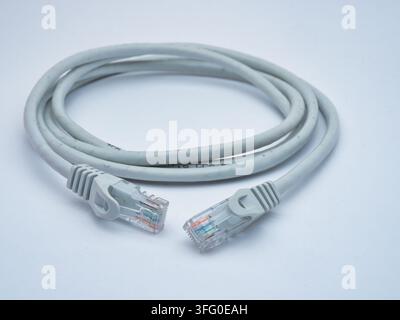 Grey Ethernet Cable with RJ45 Connectors - A coiled grey Ethernet cable with two RJ45 connectors on a clean white background, ready for network connec Stock Photo