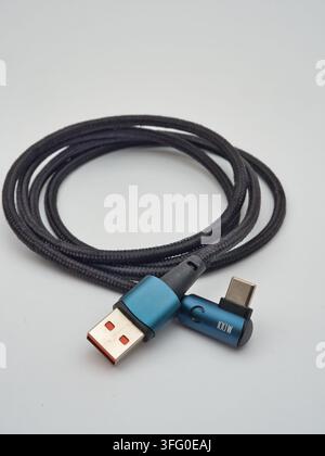 Black Braided USB-A Cable on White - A black braided USB-A connector cable is coiled on a clean white background, ready for charging or data transfer. Stock Photo