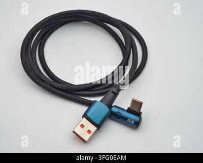 Black Braided USB-A Cable on White - A black braided USB-A connector cable is coiled on a clean white background, ready for charging or data transfer. Stock Photo