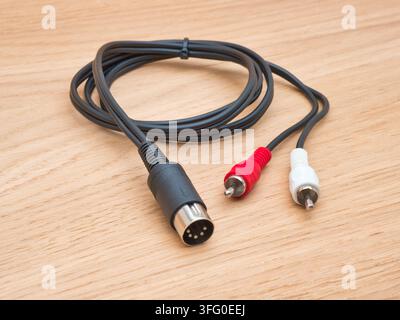 S-Video and RCA Audio Cable on Wood - A black S-Video cable with red and white RCA audio connectors rests coiled on a light wooden background, ready f Stock Photo