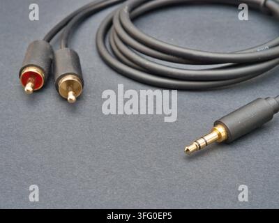 Black Audio Cable RCA to 3.5mm Jack - A black audio cable with gold-plated RCA connectors on one end and a 3.5mm jack on the other, coiled neatly on a Stock Photo