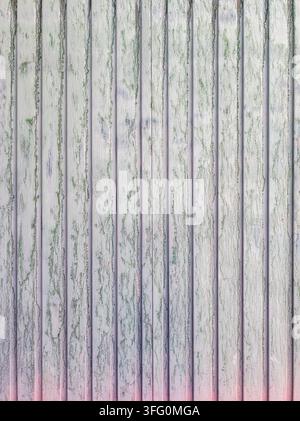 Close-up view of a weathered corrugated metal surface. Faded green paint peels away, revealing lighter tones and subtle hints of blue and pink. Stock Photo