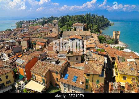 High-angle aerial view over the terracotta rooftops of Sirmione historic old town, looking toward Lake Garda and the peninsula tip in Italy. Stock Photo