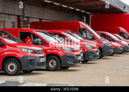 Royal Mail post office delivery vehicles parked outside of a large regional sorting office ready to be loaded with mail for delivery. Stock Photo