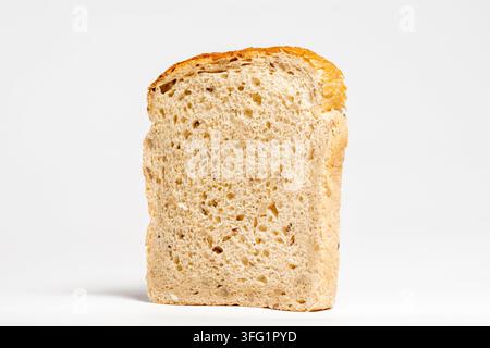 A slice of whole grain bread with a golden crust, isolated on a plain background, Single slice of mixed seeds bread side view on white Stock Photo