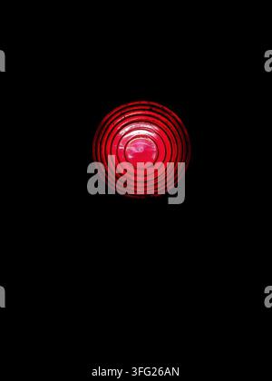 Red traffic light signal glows brightly in complete darkness. Clear stop signal symbolizes danger warning and immediate halt. Stock Photo