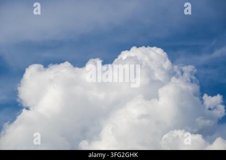 Dramatic fluffy white cumulus cloud formation rising against a bright blue atmospheric sky. Concept for optimism, climate studies, weather forecasting Stock Photo