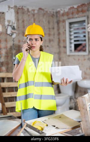 Woman talking on phone at building site Stock Photo
