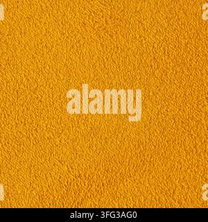 Detailed macro view of a golden yellow textile showing a dense felted fiber structure with a smooth tactile finish under even light Stock Photo