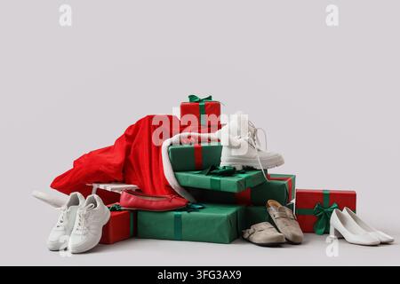 Holiday shopping and seasonal sales, pile of gift boxes with various footwear and santa claus costume on a light background Stock Photo