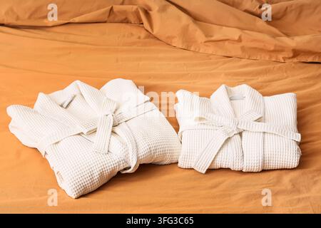 Folded waffle bathrobes on bed in room Stock Photo