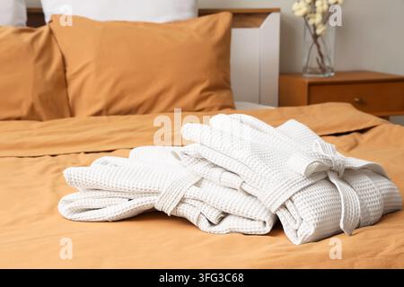 Folded waffle bathrobes on bed in room Stock Photo