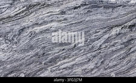 Close-up of a high-resolution natural granite slab featuring dynamic gray-black swirling veins, fine granular texture, and subtle depth under even lighting. Stock Photo