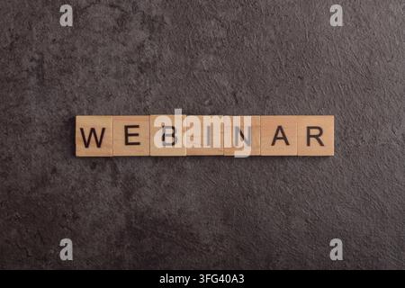 Wooden letter blocks spelling webinar on a dark textured background, representing online education, virtual training, remote learning, digital events Stock Photo