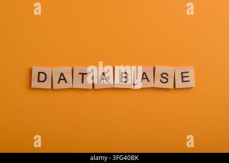 Wooden letter blocks spelling database on an orange background, representing data storage, information management, digital technology, computing Stock Photo