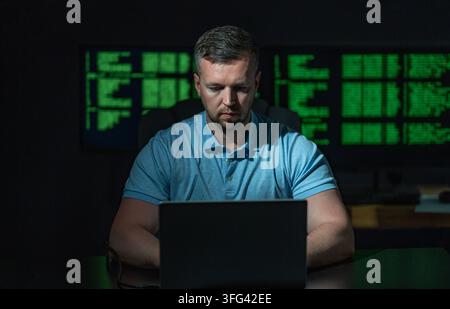 Programmer develops secure software system. Programmer writes programming on computer screen. Programmer monitors network and server logs. Programmer Stock Photo