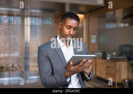 Black businessman standing in office holds digital tablet Stock Photo
