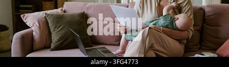 Woman Breastfeeding Baby While Working from Home with Laptop Stock Photo