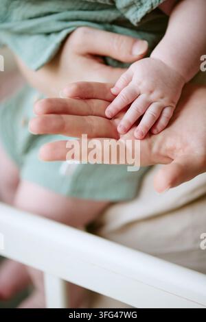 Mother Holding Baby Hand at Home for Childcare Concept Stock Photo