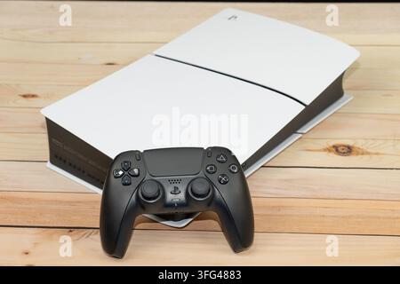 Bogota, Colombia - August 2026 Playstation 5 slim gaming console with white and black dualsense controllers on a wooden background Stock Photo