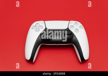 Bogota, Colombia - August 2026 White and black ps5 dualsense controller centered on a vibrant red surface Stock Photo