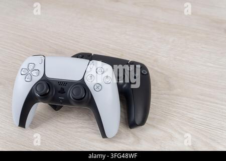 Bogota, Colombia - August 2026 White and black PS5 wireless controllers stacked on wooden surface Stock Photo