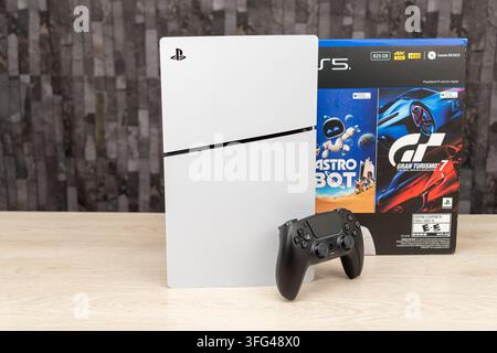 Bogota, Colombia - August 2026 Hand holding a playstation 5 dualsense controller with console and games in background Stock Photo