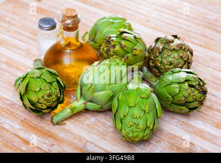 Green artichokes, oil and salt on table Stock Photo