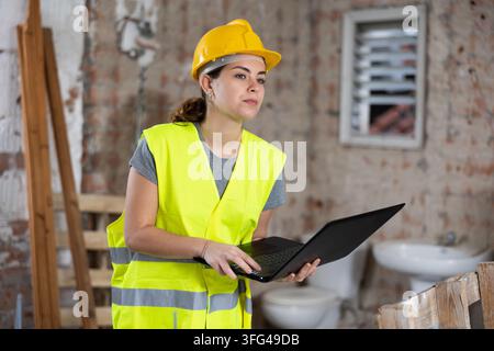 Female engineer using laptop in apartment Stock Photo