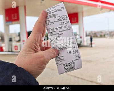 Perm, Russia - May 4, 2026: Hand holds a small printed gasoline receipt ...