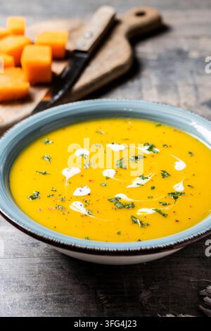 Creamy pumpkin soup with herbs and cream on wooden table Stock Photo