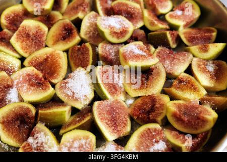 Freshly sliced figs arranged in a baking dish, generously topped with white sugar, ready for cooking and creating a sweet, healthy dessert or ingredie Stock Photo