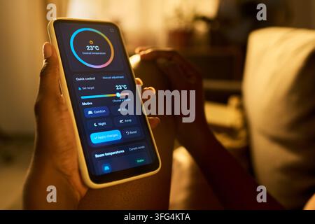 Close-Up of Woman Using Smart Home Application on Smartphone at Home Stock Photo