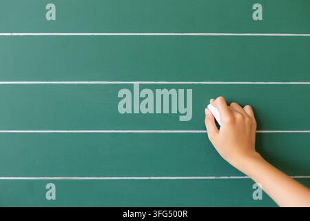 A student wipes the chalkboard in a school classroom during a study session, getting ready for upcoming lessons and activities. Stock Photo