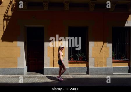Young woman walking on a sunny city sidewalk Stock Photo