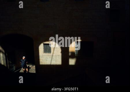 Man with backpack walks through a sunlit stone archway Stock Photo