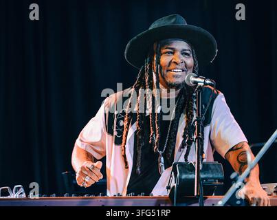 Smiling musician with dreadlocks playing keyboard on stage Stock Photo