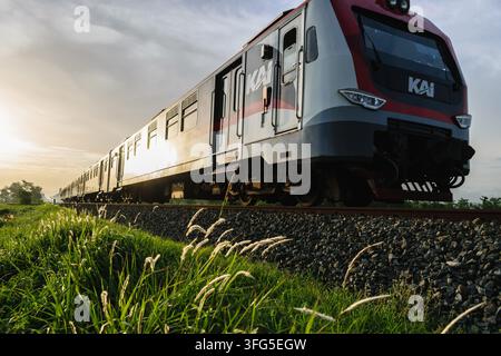 Indonesian YIA Airport commuter train KRDE (KAI kereta api Indonesia) traveling on Sunset Light near Patukan Station, Sleman, Yogyakarta. Stock Photo