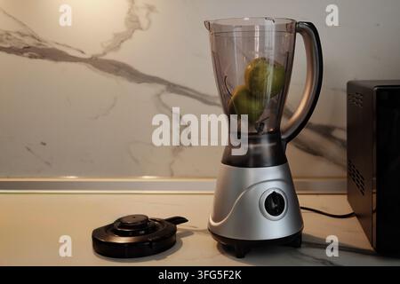 Countertop blender with fresh green apples prepared for blending in a bright home kitchen, representing healthy homemade drinks,fresh food preparation Stock Photo