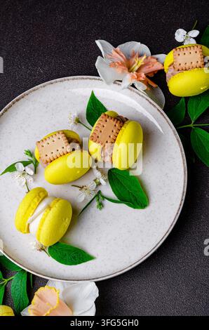 Yellow Macarons with Cookies and White Flowers on a Ceramic Plate Stock Photo