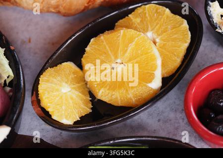 Fresh orange slices are placed on a black dish with other food. Stock Photo