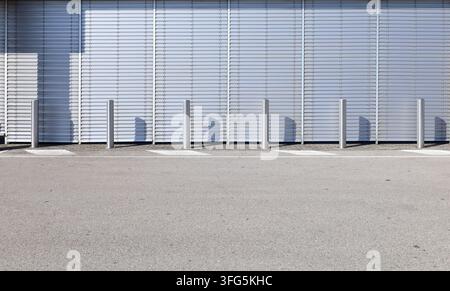 Metallic venetian blinds shutters on glass facade at the roadside. Bollards on sidewalk and road markings. Background for copy space Stock Photo