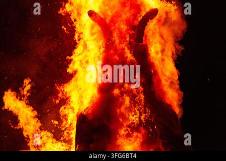 FACE OF THE BURNING WICKER MAN, BURNING THE WICKER MAN EFFIGY, GREEN MAN FESTIVAL, BRECON, WALES, UK, 2018: Intense red and yellow flames define the face and horns of a large burning effigy against the black night sky. Photo: Rob Watkins. INFO: The Green Man Festival is held annually in the Brecon Beacons in August. It celebrates music, arts, literature, science and family-friendly culture in a beautiful mountain setting. Each year the festival ends with the ritual burning of the wicker man Green Man effigy. Stock Photo