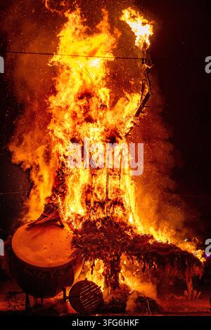 BURNING WICKER MAN EFFIGY AT NIGHT, BURNING THE WICKER MAN EFFIGY, GREEN MAN FESTIVAL, BRECON, WALES, UK, 2019: A large wicker effigy with a distinctive arm-like structure on its right side burns with intense orange flames at a night-time festival. Photo: Rob Watkins. INFO: The Green Man Festival is held annually in the Brecon Beacons in August. It celebrates music, arts, literature, science and family-friendly culture in a beautiful mountain setting. Each year the festival ends with the ritual burning of the wicker man Green Man effigy. Stock Photo