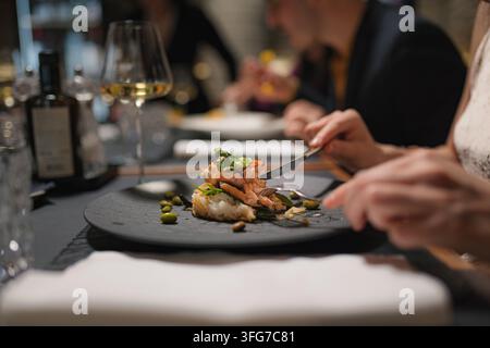 Group of friends dine together in upscale restaurant enjoying their meal and drinks. Stock Photo