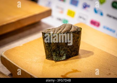 Kanimiso (crab tomalley) gunkan maki sushi served on a traditional wooden geta tray in a Japanese restaurant. Kanimiso is made from the rich, savory i Stock Photo