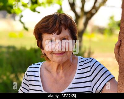 Smiling senior woman enjoying active retirement in summer garden Stock Photo