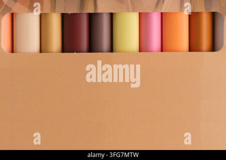 Row colorful pastel wax crayons or leads visible through horizontal cut window in cardboard packaging Stock Photo