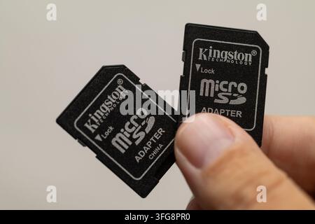 Los Angeles, California, USA - September 09, 2026: Two Kingston microSD adapters held by hand, showing black memory card adapters with visible brandin Stock Photo