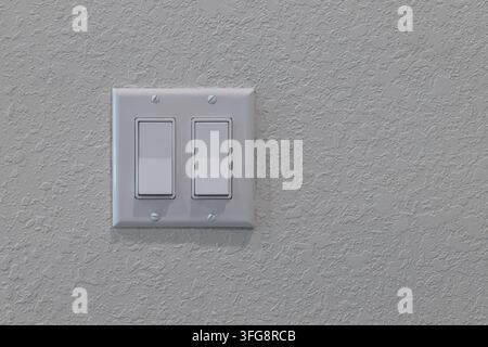White double light switch mounted on textured wall with four visible screws, clean residential interior and copy space Stock Photo